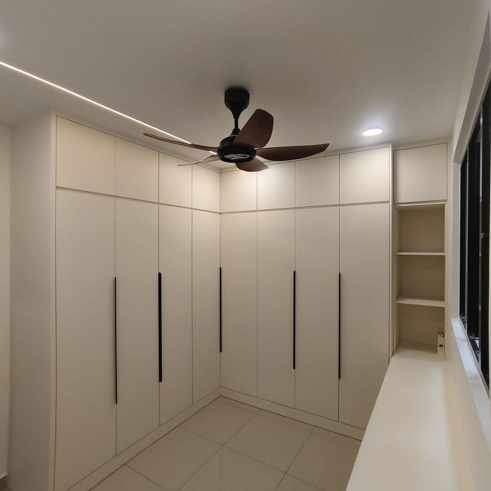 A full-wall built-in wardrobe run in cream, floor to ceiling, in a finished bedroom.